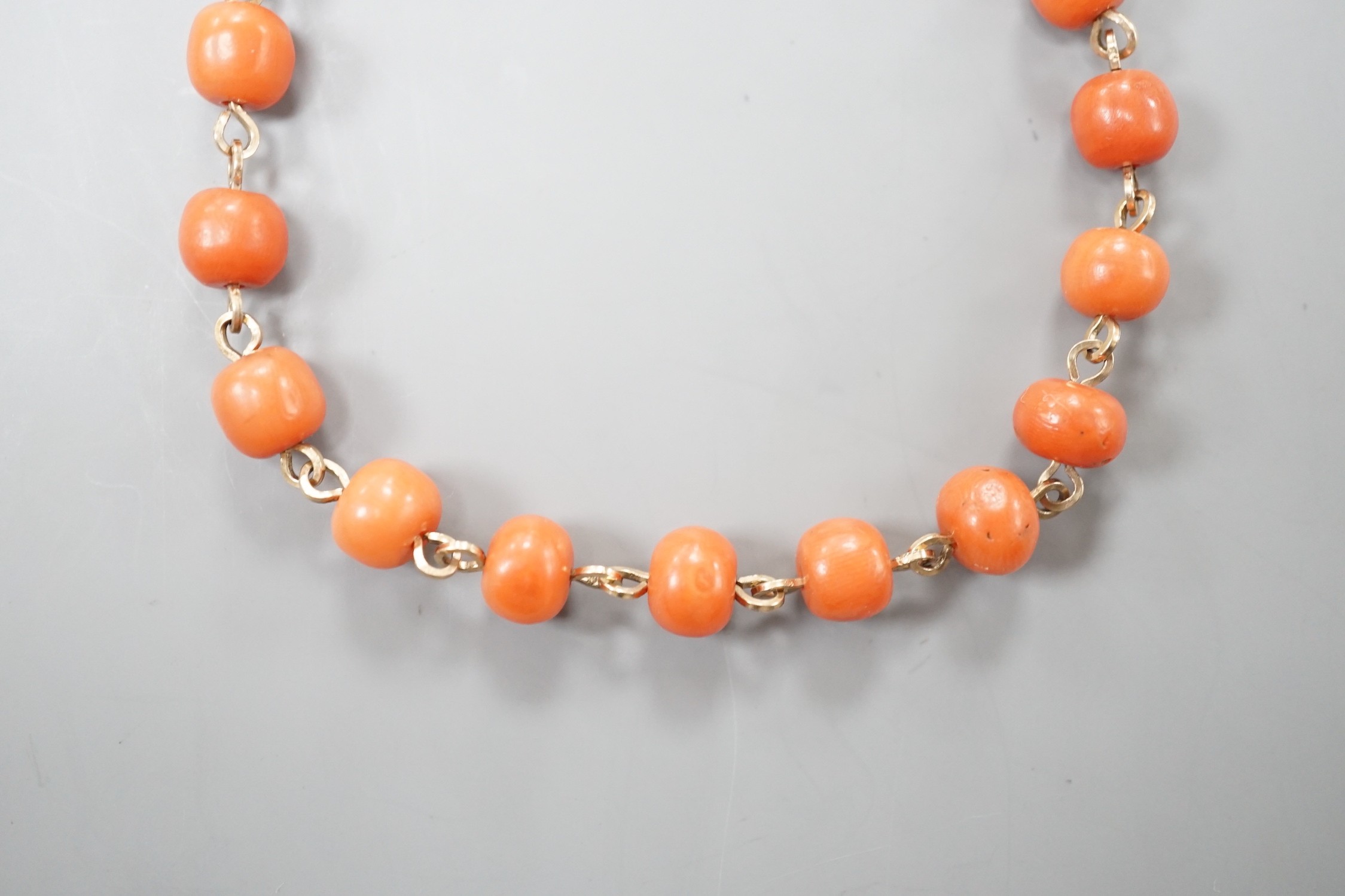 A yellow metal and coral bead bracelet, with carved coral bead clasp, 19.5cm.